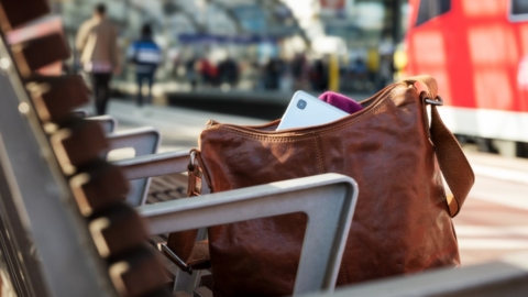 Tasche mit Smartphone, Bankm, Gleis am Bahnhof